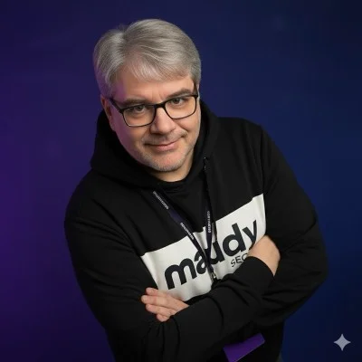 Maudy Pedrão, consultor de SEO independente, de braços cruzados, com óculos e moletom preto com o logo maudy SEO
